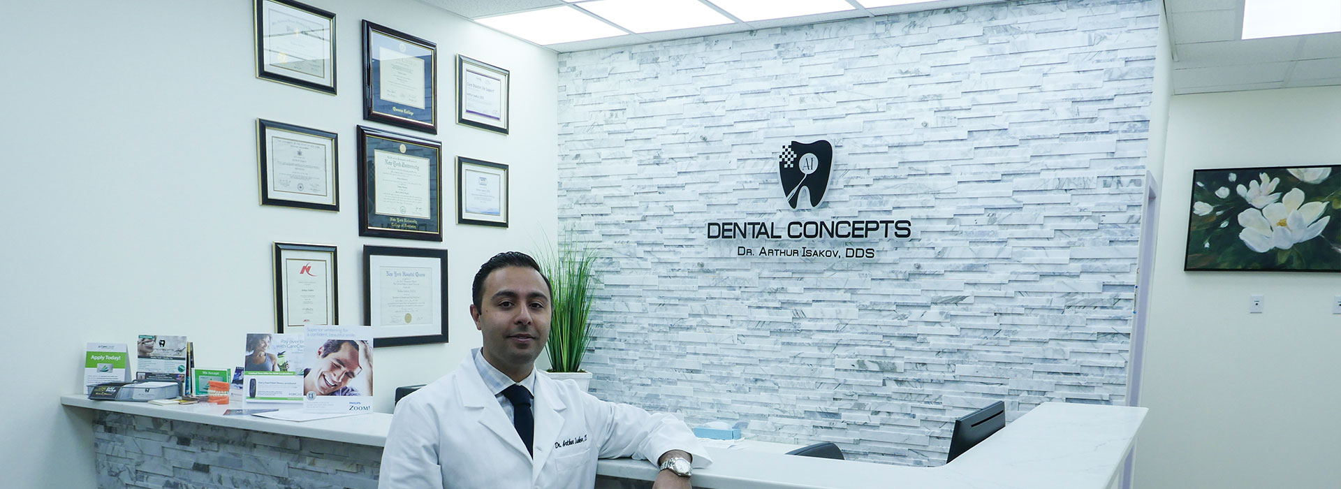 A professional standing behind a desk with a sign reading  Dental Concepts  above it.