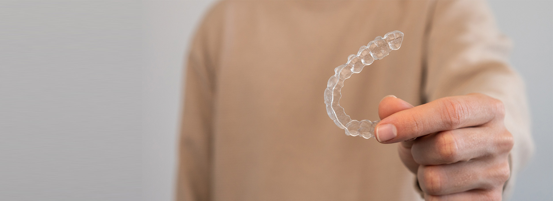 The image shows a hand holding a transparent plastic object with a spiral pattern, which appears to be a piece of plastic wrap or a similar item, against a blurred background that suggests an indoor setting.