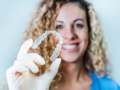 The image shows a person holding up a dental implant with a smile, demonstrating its size and appearance.