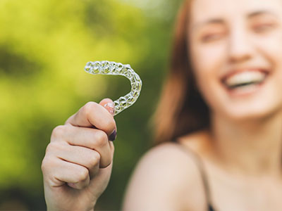 A person is holding up an oversized toothbrush with a smile on their face.