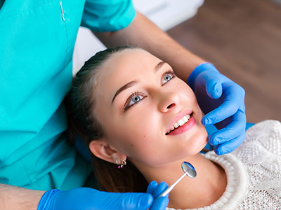 A woman receiving dental care from a professional, with her mouth open wide for examination or treatment.